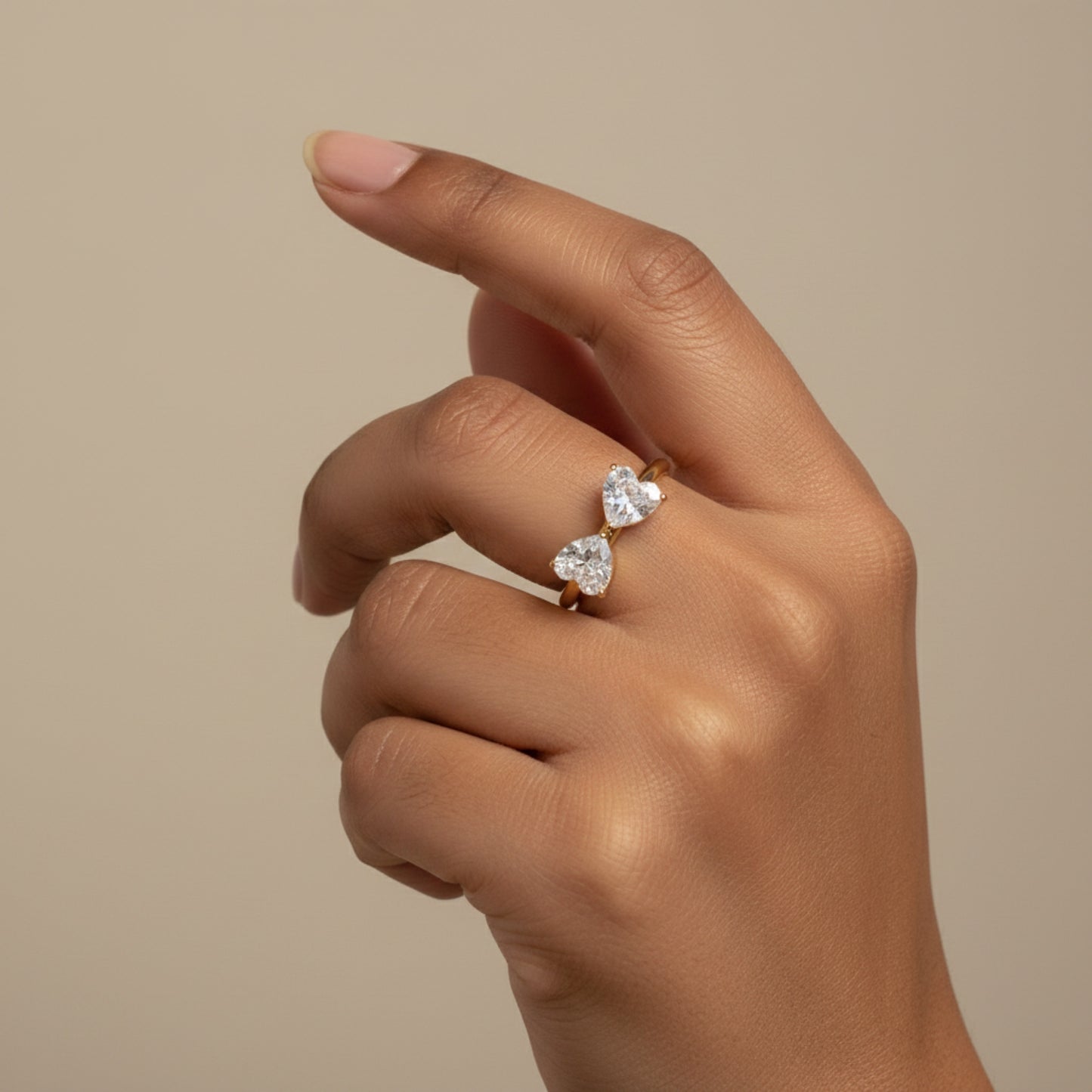 Model wearing a double heart toi et moi ring with two heart-shaped crystals on a delicate gold-tone open band